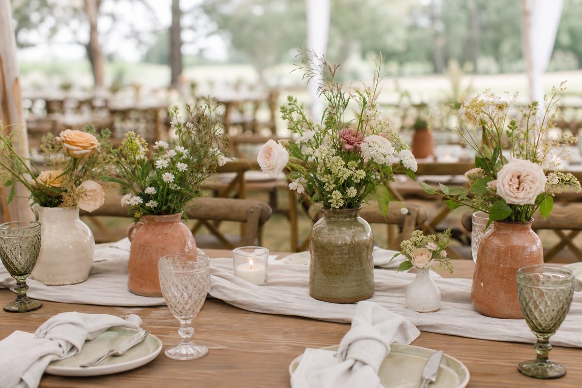 Rustic wedding table decorated with handmade ceramic vases filled with garden flowers