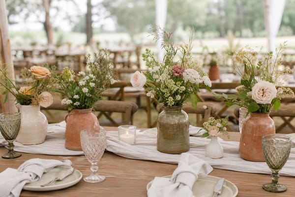 Rustic wedding table decorated with handmade ceramic vases filled with garden flowers